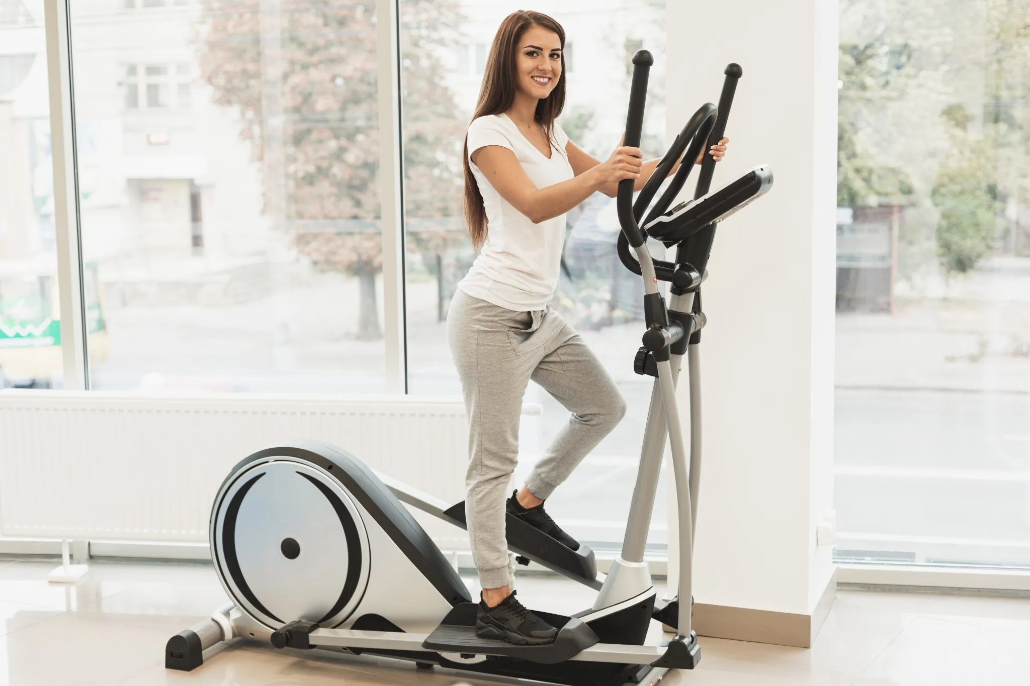 A woman exercising on a modern elliptical machin inside a brightly lit room