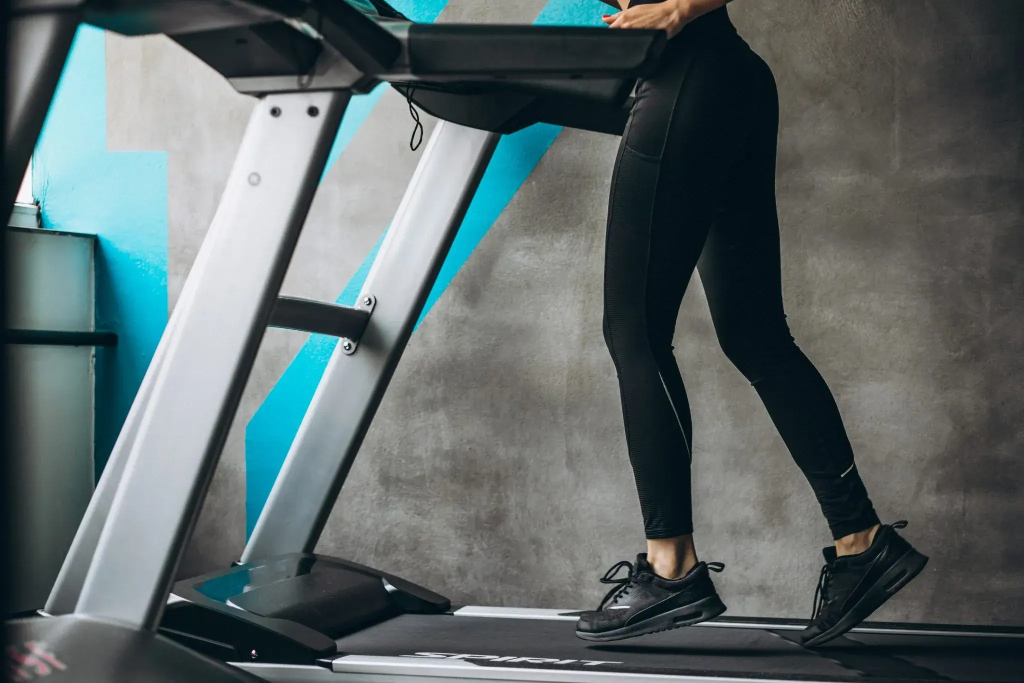 A person's lower body is shown actively running on a treadmill